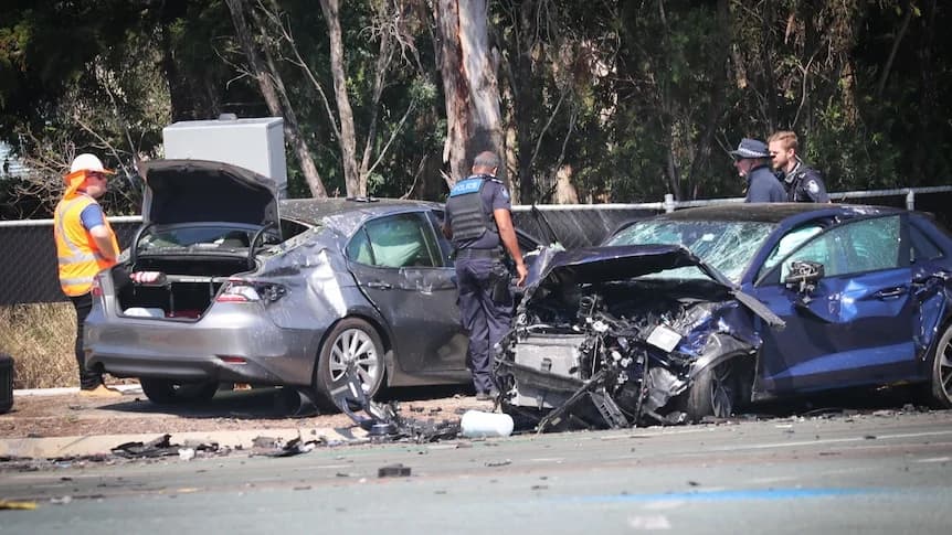 Two grey cars on country road with trees, one car has front smashed up, other has side and has boot open. SES and police stand